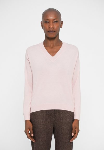 Maglione rosa a scollo a V con maniche lunghe, realizzato in materiale morbido. Presenta un bordo e polsini a coste, abbinato a pantaloni marroni texturizzati.