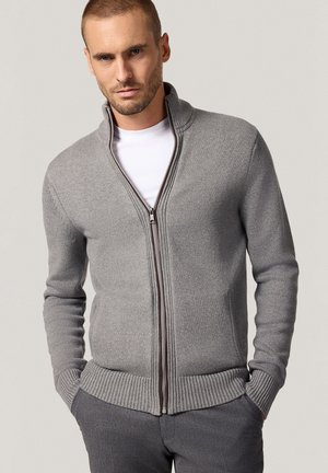 Szara bluza zapinana na zamek z prążkowanym kołnierzem i mankietami, charakteryzująca się gładką dzianiną i kontrastującym brązowym zamek.