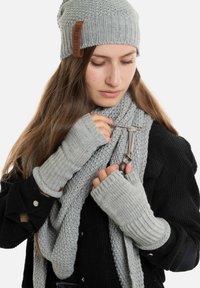 Grijze gebreide beanie, vingerloze handschoenen en een stevige sjaal, met een gestructureerd patroon en leren accentdetails.
