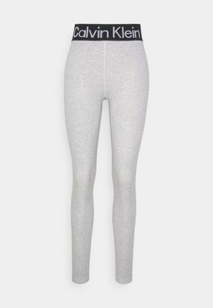 Leggings grigio chiaro con una cintura elastica nera che presenta in modo prominente il logo bianco "Calvin Klein". Tessuto liscio e elastico.