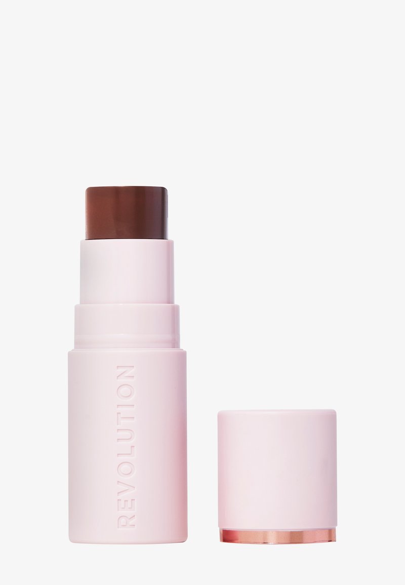 Revolution stick foundation i en ljusrosa tub, med ett mörkbrunt vridapplicator och ett avtagbart lock, som har en guldaccent i botten.