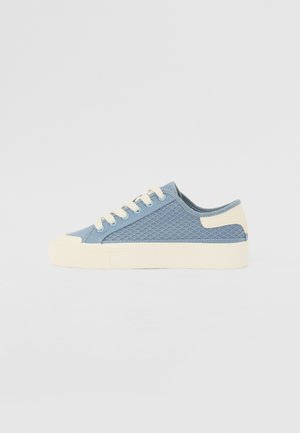 Sininen verkkokenkä vaaleanruskealla kumipohjalla, pyöristetty kärki ja tasaiset nauhat. Sivustoilla on teksturoidut kuviot ja pehmustettu kaulus.