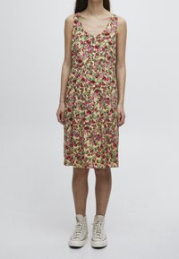 Vestido midi floral con flores rosas y verdes sobre un fondo claro, con escote redondo, detalles de botones y cintura fruncida.