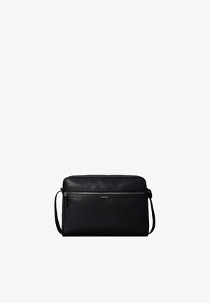 Sac bandoulière noir Calvin Klein avec texture perforée, poche avant zippée et sangle d'épaule réglable sur fond blanc.