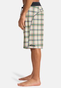 Καρό μαγιό σορτς σε κρέμ, καφέ και πράσινο χρώμα· κατασκευασμένα από ελαφρύ ύφασμα με μαύρη ζώνη μέσης, πλαϊνές τσέπες και σούρα στη μέση.