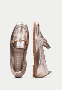 Mocassini in rosa oro metallico con finitura in pelle testurizzata, design con tacco aperto, accessori in metallo e suola in gomma flessibile.