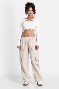 Witte cropped longsleeve top met een uitsnijding, gecombineerd met beige cargobroek met voorzakken, elastische taille en trekkoord.