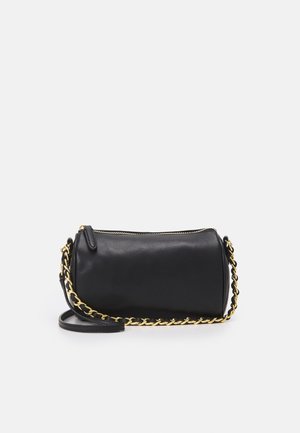 Zwarte cylindrische leren handtas met gouden ketting en zwarte band, voorzien van een bovenste ritssluiting op een effen lichte achtergrond.