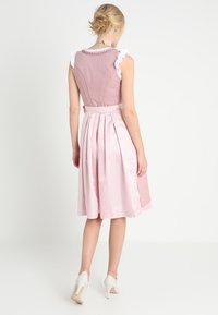 Růžový dirndl s přiléhavým korzetem, nabíranými rukávy a sukní s kostkovaným vzorem. Obsahuje sklady a stuhu jako pásek.