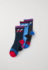 Tre paia di calze alla caviglia FILA, in nero, blu e nere con accenti rossi e blu, disposte a ventaglio su sfondo bianco.
