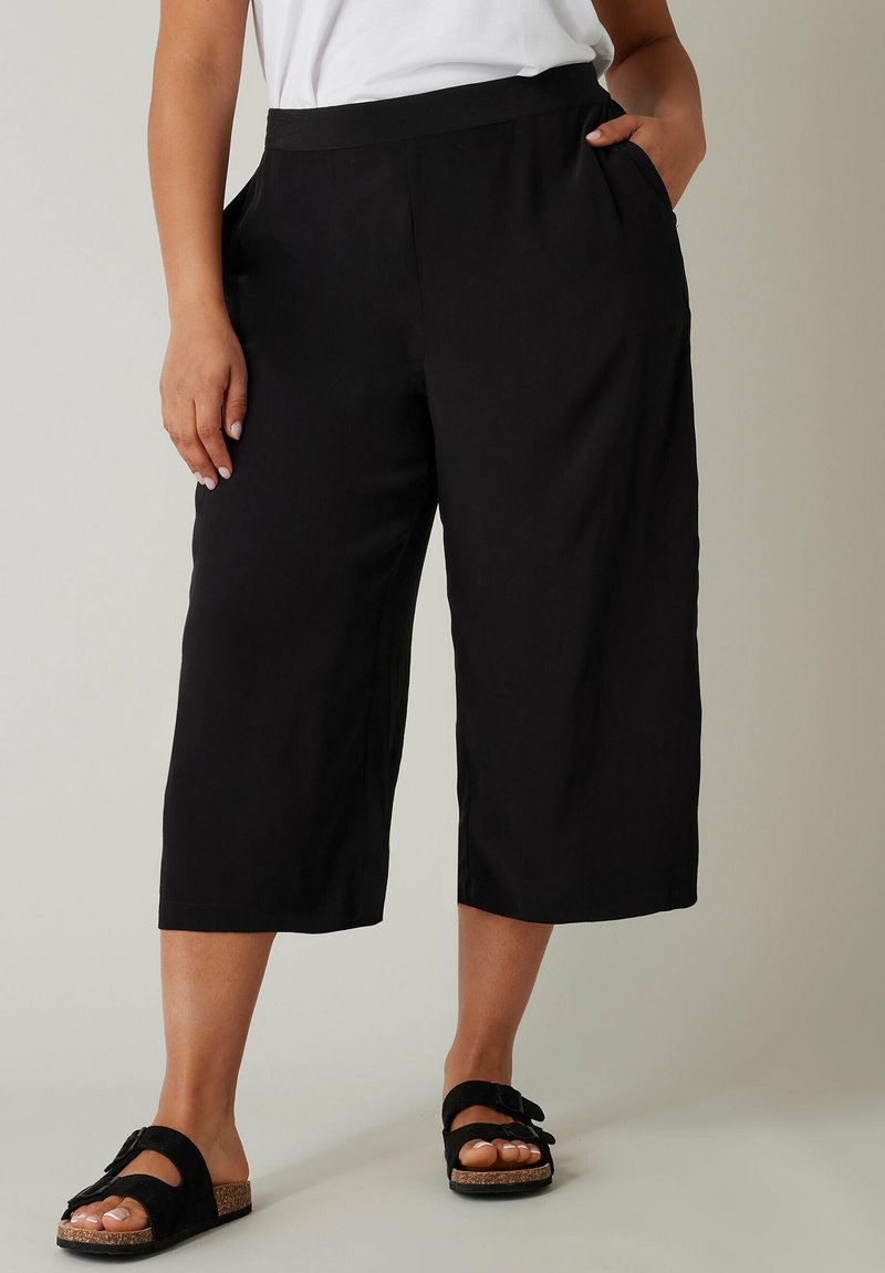 Zwarte culottes van lichtgewicht stof, met een gladde textuur, zijzakken en een relaxte pasvorm, eindigend op de kuit.