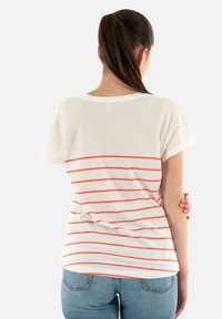 Camiseta blanca con rayas coral en horizontal, cuello redondo y mangas cortas, hecha de una tela ligera, con un corte relajado.