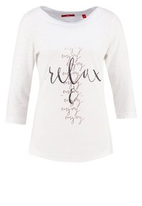 Weißes Langarmshirt mit lässiger Passform, Rundhalsausschnitt und metallic-farbigem Textdesign, das "entspannen" und "genießen" in verschiedenen Stilen darstellt.