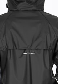Giacca nera impermeabile con una texture liscia, dotata di cappuccio e bottoni. Logo "SWEDEMOUNT" stampato in bianco sulla schiena.