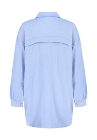 Light blue loose-fitting shirt featuring a textured fabric, long sleeves with button accents, and a classic collar. Back has a yoke design.