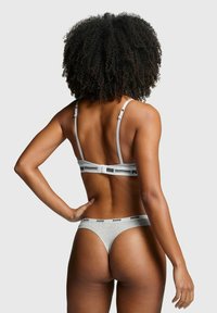 Graues Thong- und Bralette-Set von Puma, mit weichem Stoffmaterial, verstellbaren Trägern und Logo-Akzenten am Bund.