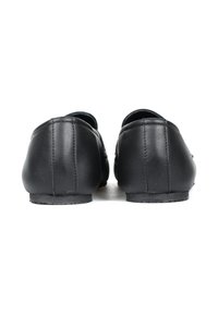 Czarne skórzane buty o gładkiej teksturze, zaokrąglonym kształcie, minimalnych detalach szwy oraz niskoprofilowych gumowych podeszwach. Widok z tyłu.