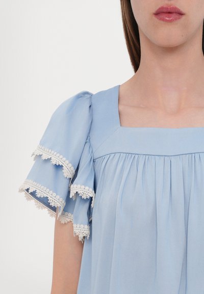 Top azzurro chiaro con scollatura quadrata, design plissettato e maniche corte a sbuffo con bordi in pizzo bianco e volants.