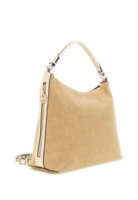 Beżowa zamszowa torba hobo z kremowym skórzanym paskiem, złotym zamkiem błyskawicznym i odpinanym cienkim paskiem na ramię na białym tle.