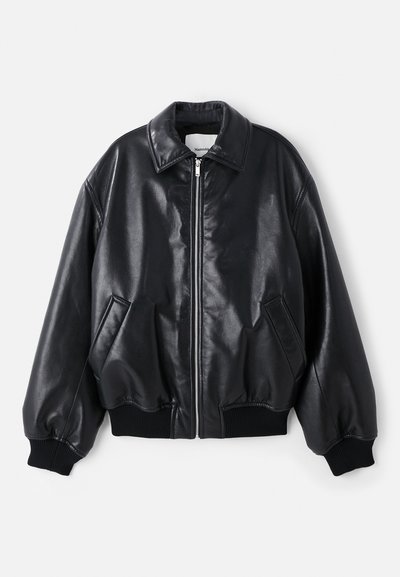 Melna ādas bumbvedēju jaka ar rāvējslēdzēju priekšā, lielu apkakli, sānu kabatām un ribotiem piedurkņu galiem un apakšmalu. Gluda, spīdīga tekstūra.