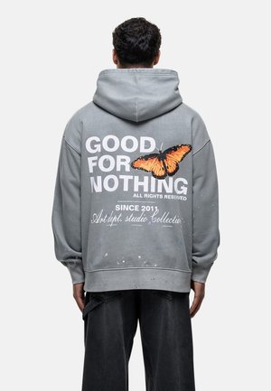 Grijze oversized hoodie met een vlinderafbeelding en tekst op de achterkant. Heeft een spetterontwerp, ribgebreide manchetten en een kangoeroezak.