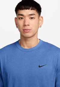 Kék, hosszú ujjú ing, puha anyagból készült, kerek nyakkivágással, a bal felső oldalon egy kis fekete Nike logóval.
