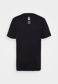 Camiseta de algodón negra con cuello redondo, mangas cortas y un detalle de logo en blanco en la parte posterior, que presenta una forma y textura sencillas.