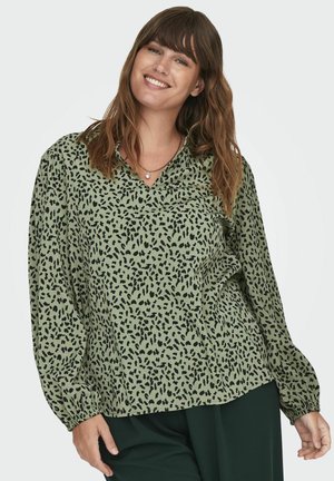 Chemisier vert avec imprimé léopard noir, manches longues, décolleté en V et poignets froncés. Tissu doux avec une coupe décontractée.