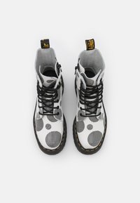 Schoenen: zwart-witte enkellaarsjes met een stippenpatroon, gestructureerd leer, zwarte veters, gele stiksels en een trekhaak op de hiel.