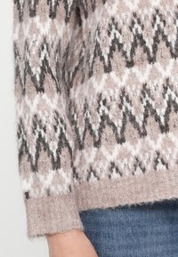 Sweter dzianinowy w zygzakowy wzór w delikatnym różowym, białym i czarnym kolorze. Posiada przyjemną w dotyku fakturę oraz ściągacz na dole.