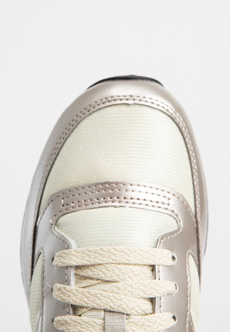 Zapatillas con parte superior de textil crema y acentos metálicos plateados, malla texturizada, puntera redonda y cordones beige.