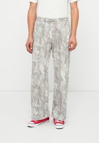 Light gray, floral-patterned sweatpants with an elastic waistband and drawstring. Paired with red low-top sneakers.