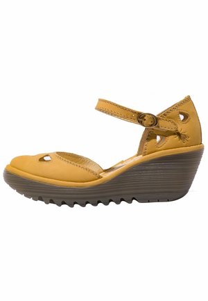 Sandale compensée en cuir jaune avec détails découpés, bride à la cheville et semelle crantée foncée.