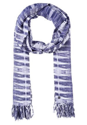 Blauw-witte sjaal met patroon en franjes aan de uiteinden, gewikkeld in een lus met een klein rond metalen labeltje vlakbij een van de franjes.