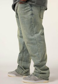 Ljusblå denimjeans med avslappnad passform, med sidofickor och sydda detaljer. Matchad med grå sneakers.