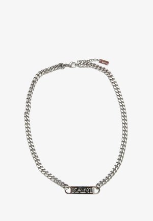 Zilveren ketting met dikke schakels, een rechthoekig label met "KANI" in het zwart. Inclusief een veilige sluiting en extra ketting voor maatregeling.