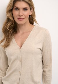 Beige cardigan with a V-neck, long sleeves, and button closure. Soft texture with a subtle knit pattern. Simple and versatile design.