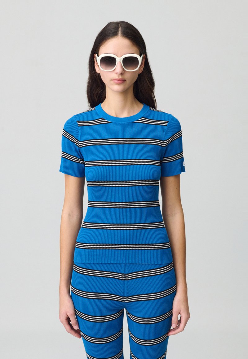 Maglietta a righe blu in maglia a coste, con linee orizzontali bianche e nere, maniche corte e scollo rotondo, abbinata a pantaloni slim-fit a righe coordinate.