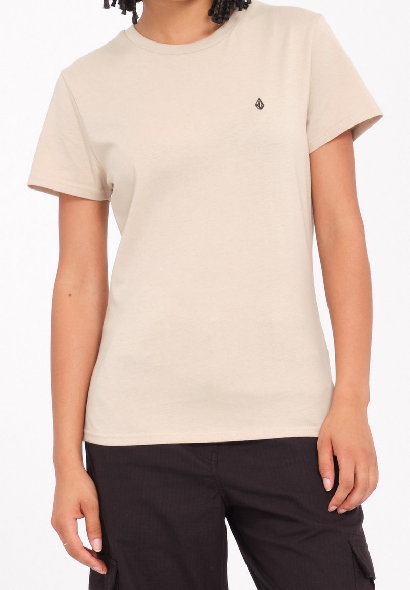 T-shirt in cotone beige con scollo rotondo, maniche corte e un piccolo logo nero sul lato sinistro del petto; texture liscia e vestibilità classica.