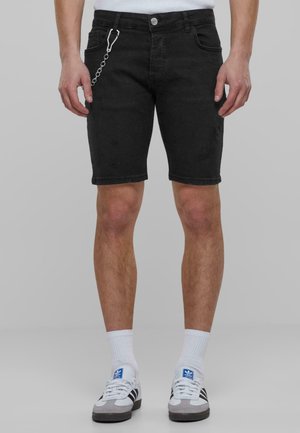 Pantalones cortos de mezclilla negra con un corte ajustado, que presentan un detalle de cadena en la cintura y elementos sutiles desgastados. Diseño clásico de cinco bolsillos.