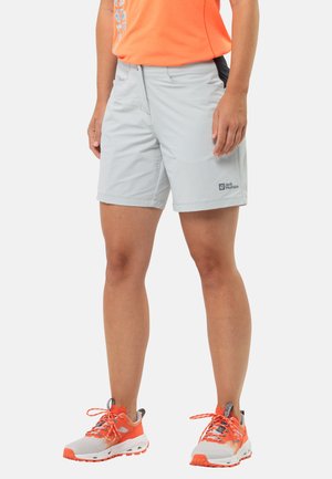 Helle graue Shorts mit Taschen und schwarzen Akzenten, aus einem flexiblen Material gefertigt. Dazu werden weiße und orange Trail-Schuhe mit strukturierten Sohlen getragen.