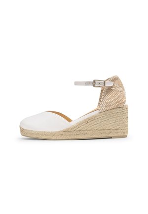 Sandalia cuña blanca cerrada en la puntera con suela trenzada de yute, tacón tejido beige y correa ajustable en el tobillo con hebilla plateada.
