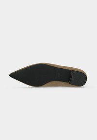 Chaussure plate en daim beige à bout pointu vue de la semelle avec semelle en caoutchouc noir et talon texturé.