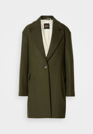 Cappotto in misto lana verde scuro con revers a punta, chiusura a un bottone e tasche laterali. Interno con una leggera fodera trapuntata.