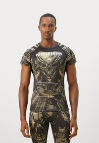 Black and gold graphic athletic shirt featuring an alien skull design, smooth texture, short sleeves, and a round neckline.