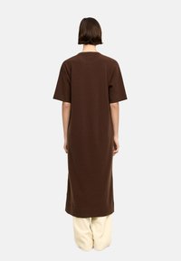 Brąsowa sukienka do kolan z krótkimi rękawami, wykonana z teksturowego materiału. Prosty krój, okrągły dekolt oraz boczne rozcięcia dla ułatwienia ruchów.