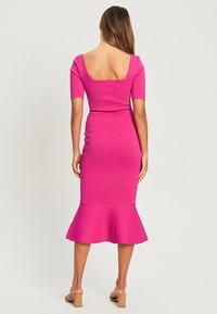 Abito rosa aderente con orlo svasato, maniche corte e schiena quadrata. Realizzato in tessuto lucido che mette in risalto la silhouette.
