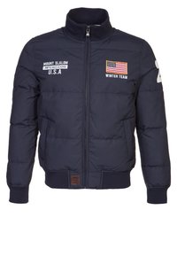 Navy puffer jacket with a high collar, front zipper, embroidered logos, U.S. flag, and ribbed cuffs. Features a padded design for warmth.