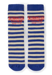 Calzini a righe blu e bianche con logo rosso "Stranger Things Benetton" vicino alla parte superiore, posati distesi affiancati su sfondo bianco.