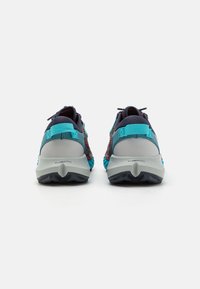 Paire de chaussures de sport bleu et marine avec semelles grises et marquage "FLOATPRO" vue de derrière sur un fond blanc.